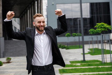 Young attractive elegant man standing near a building outdoors,