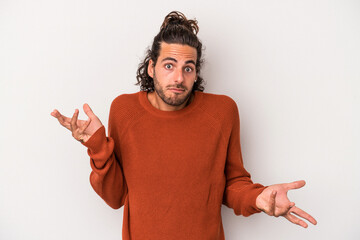 Young caucasian man isolated on gray background doubting and shrugging shoulders in questioning...