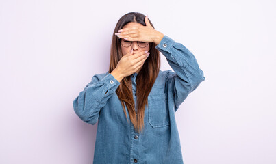 pretty hispanic woman covering face with both hands saying no to the camera! refusing pictures or...