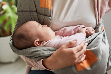 Close-up of cute baby girl sleeping while her mother holding her on hands