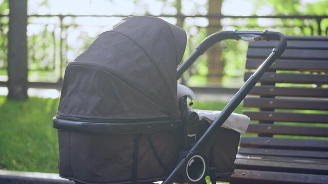 Black baby carriage near the park bench, problems of adoption, childfree choice