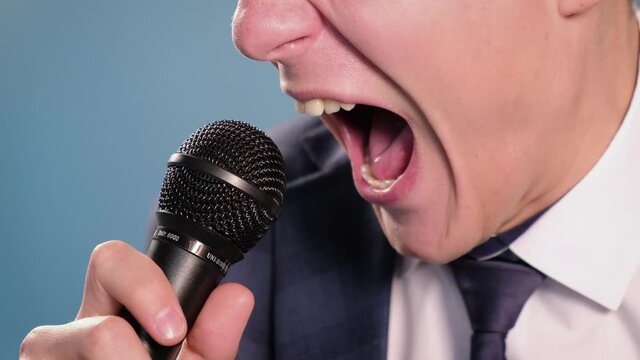 Annoyed aggressive man shouting into a microphone, close-up