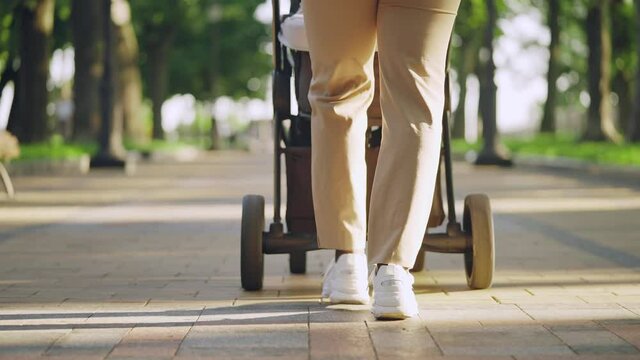 Woman in white trainers walking with baby stroller outdoors, healthy routine
