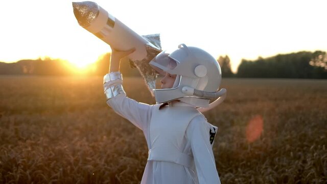Little young happy cute child boy wearing astronaut uniform and helmet cosmonaut playing, launching toy rocket at sunset field, Space man, Kid dream flying, childhood, freedom, travel, future concept