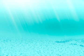 Blue underwater and sandy floor with sunlight shining down