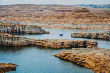 Long coastline with red rocks and cliffs, and houseboat on Lake Powell, Utah