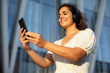 Young smiling woman with headphones outdoors. Beautiful woman listening the music.