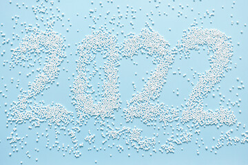 Festive abstract background in blue color with white balloons forming the inscription 2022. Creative pattern with number top view.