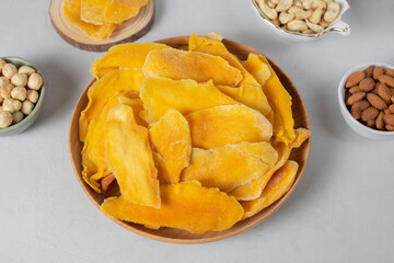 Wooden bowl dried mango fruit slices. Nuts: cashews, almonds, hazelnuts on light background. Concept natural organic healthy snack. Low sugars food- no candies. Sweets, norm of fats and oils