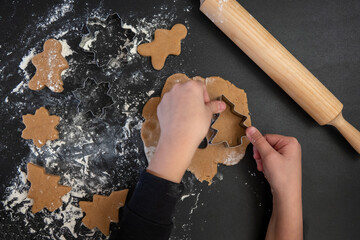 Children's hands make New Year's gingerbread cookies on a wooden table. Making cookies with a cookie cutter. New Year and Christmas concept.
