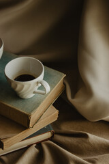 One coffee cup on top of books on an isolated beige background.