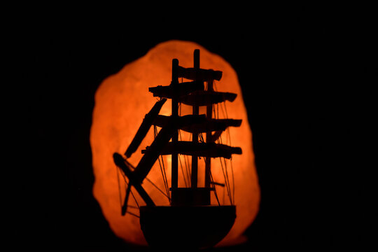 Silhouette of the model copy of a fregate in the glare of the salt stone lantern