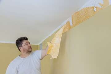 Manual work with scraper worker hand scraping old wallpaper on wall with preparation for painting a...