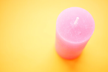 Pale pink candle on a vivid yellow table