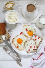 Breakfast with scrambled eggs, muesli with fruits, berries and coffee with milk on a brown wooden background	
