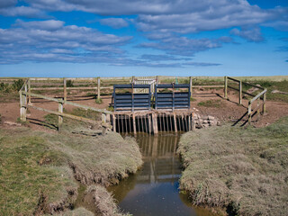 Flood defences in the low lying salt marshes around South Low near Goswick in Northumberland, England, UK. Taken on a sunny day in summer.