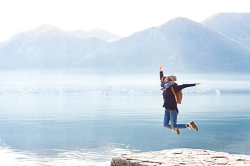 Young woman jumping at nature, winter sea beach. Traveler enjoying traveling