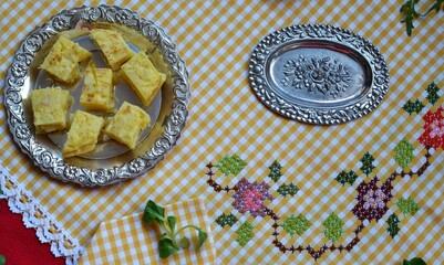 Table in yellow and red tones with a hand-embroidered tablecloth and a portion of Spanish omelette