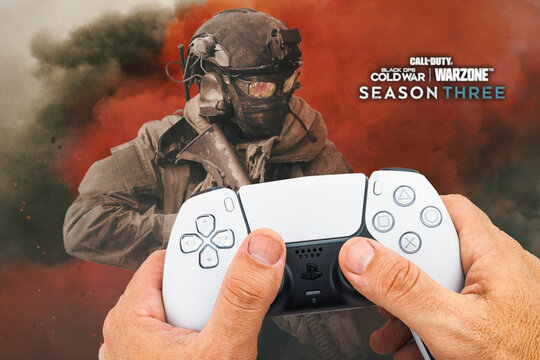 Male hand holding a Playstation 5 Dual Sense Controller with Call of Duty Season Three game blurred in the background. Rio de Janeiro, RJ, Brazil. October 2021.