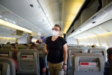 Handsome mature man in protection face mask during boarding in airplane. Safety transportation while coronavirus epidemic.