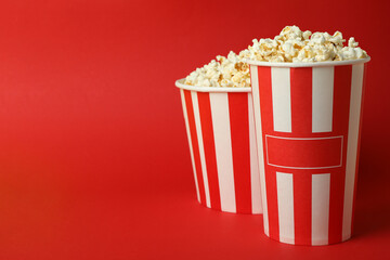 Paper cups with popcorn on red background