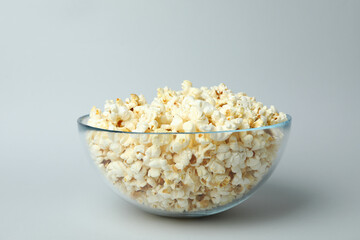 Glass bowl with popcorn on light gray background