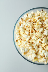 Glass bowl with popcorn on light gray background