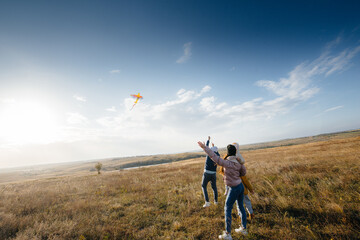 A happy family with kids launches a kite and spends time together in the fresh air. Happy childhood and family holidays.