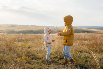 Fototapeta premium A boy and a girl play together in the field. Rejoice and laugh together.