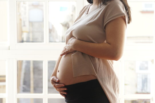 Realistic Side View of Pregnant Woman Touching Baby Bump in Natural Light