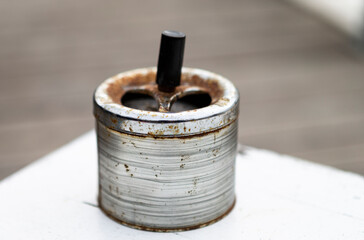 The photo shows an old rusted ashtray on a table