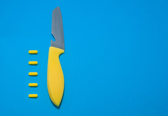 knife and pills on a blue background