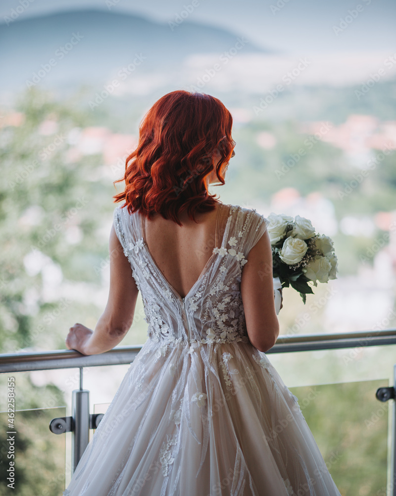 Sticker Vertical back view of the red-haired bride in a gorgeous dress holding her bouquet