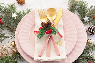 concept of christmas table setting. two pink plates, cutlery, fir branches, cones, balls and stars..