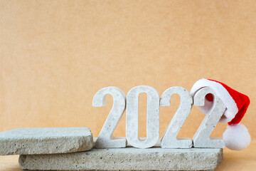 Celebrating the new year 2022. Number 2022 in concrete numerals with santa hat on concrete podiums..