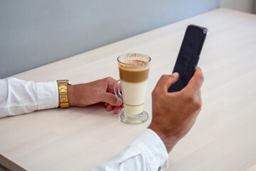 Hombre mirando el móvil. Chico chateando con el móvil. Hombre en cafetería con móvil. Hombre tomándose un café en la cafetería. Chico escribiendo con el móvil.