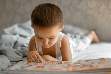 a little boy at home flips through a book and looks at pictures