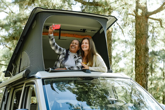 Happy diverse women taking selfie in rooftop tent