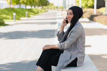 Obraz premium Adult woman smiling talking with her phone in the park looking at camera