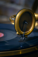 Music concept in vintage style. Close-up, vintage gold gramophone record player, read head with a needle, black record. Selective focus