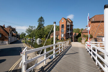 Fototapeta na wymiar Newbury, Berkshire, England, UK. 2021. White wooden swing bridge over the Kennet and Avon Canal at Newbury, tall buildings a former granary. UK