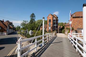 Newbury, Berkshire, England, UK. 2021.  White wooden swing bridge over the Kennet and Avon Canal at Newbury, tall buildings a former granary. UK