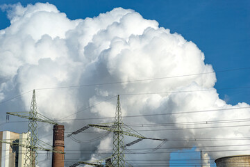 White clouds of water vapor emerging from the cooling tower of a power generating plant.