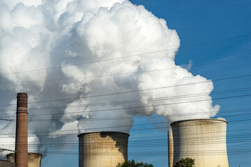White clouds of water vapor emerging from the cooling tower of a power generating plant.
