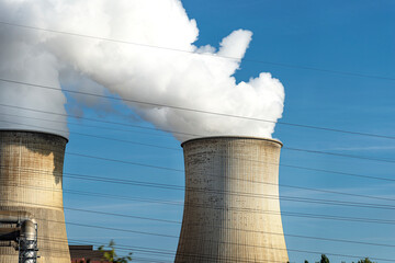 White clouds of water vapor emerging from the cooling tower of a power generating plant.
