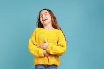Portrait of happy positive little girl laughing out loud, holding her belly, hearing funny joke,...