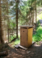 small wooden toilet in the woods of the alps