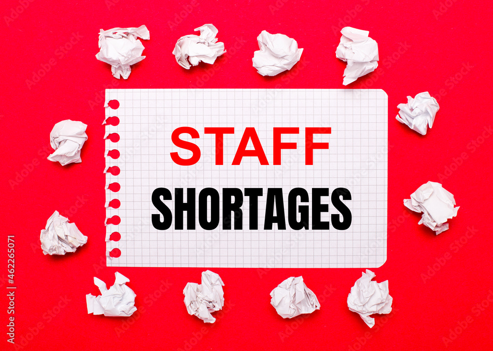 Poster on a bright red background, white crumpled sheets of paper and a sheet of paper with the text staff 