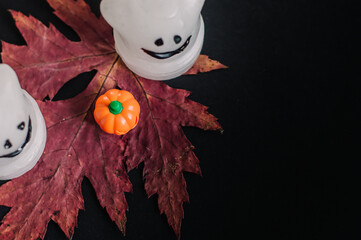 small orange pumpkin with autumn leaves,candles on a black background