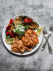 Delicious tapas barbecue plate - grilled turkey, eggplant, zucchini pepper with tzatziki sauce on a gray background, top view